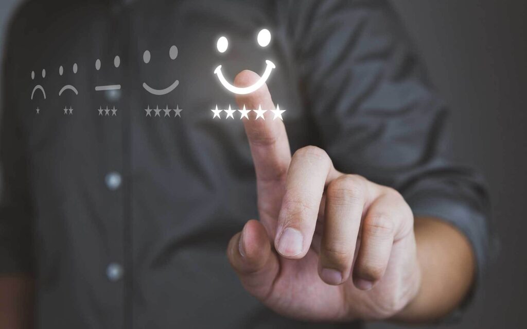 A person is about to tap a glowing five-star rating, with a series of emoticons ranging from sad to happy indicating different levels of satisfaction.
